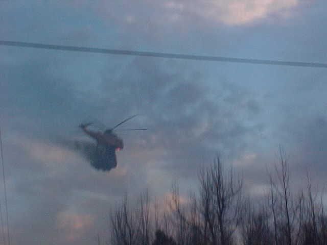 Fire fighting helicopter dumping water on the burning trees.